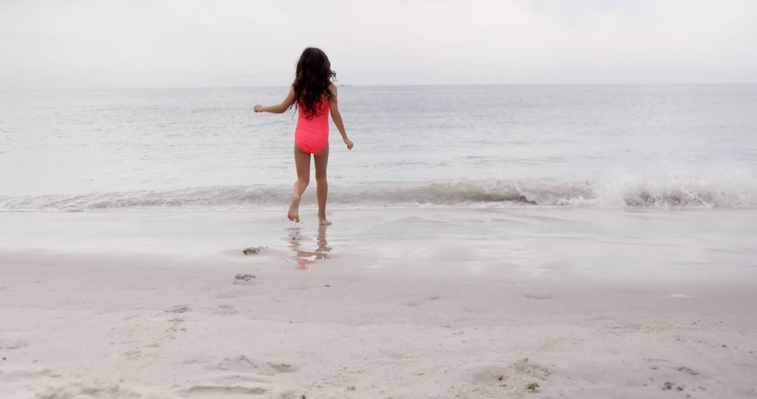 Young Girl in Swimsuit Running Toward Ocean on Beach - Free Images, Stock Photos and Pictures on Pikwizard.com