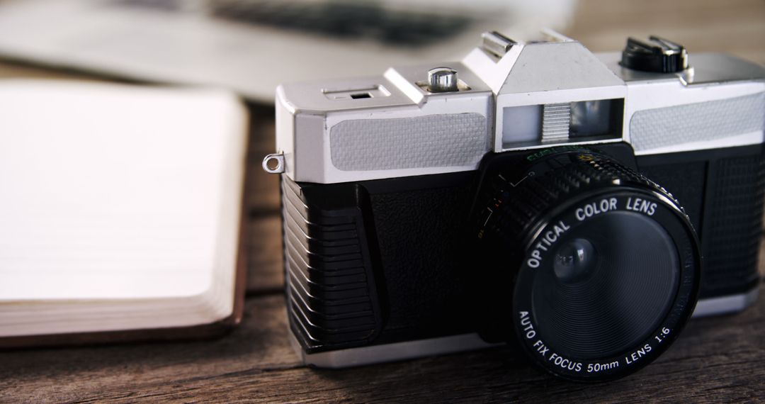 A vintage camera is positioned on a wooden surface next to an open notebook, with copy space - Free Images, Stock Photos and Pictures on Pikwizard.com