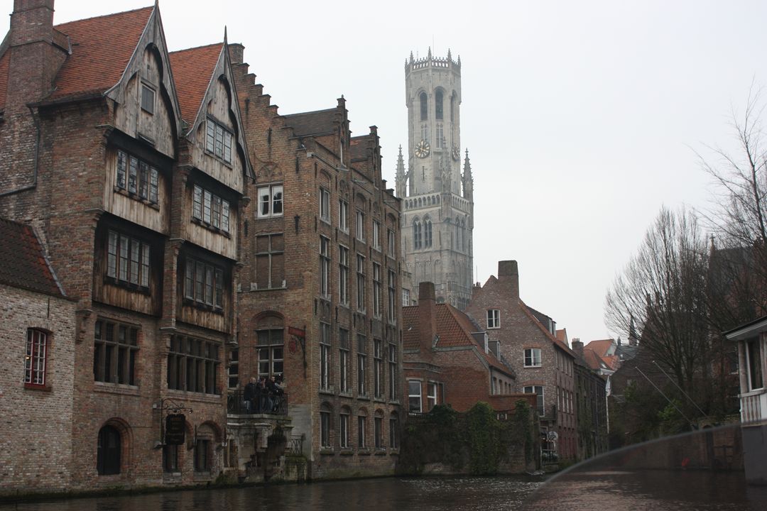 Medieval Buildings and Belfry Tower Along Canal in Foggy Bruges - Free Images, Stock Photos and Pictures on Pikwizard.com