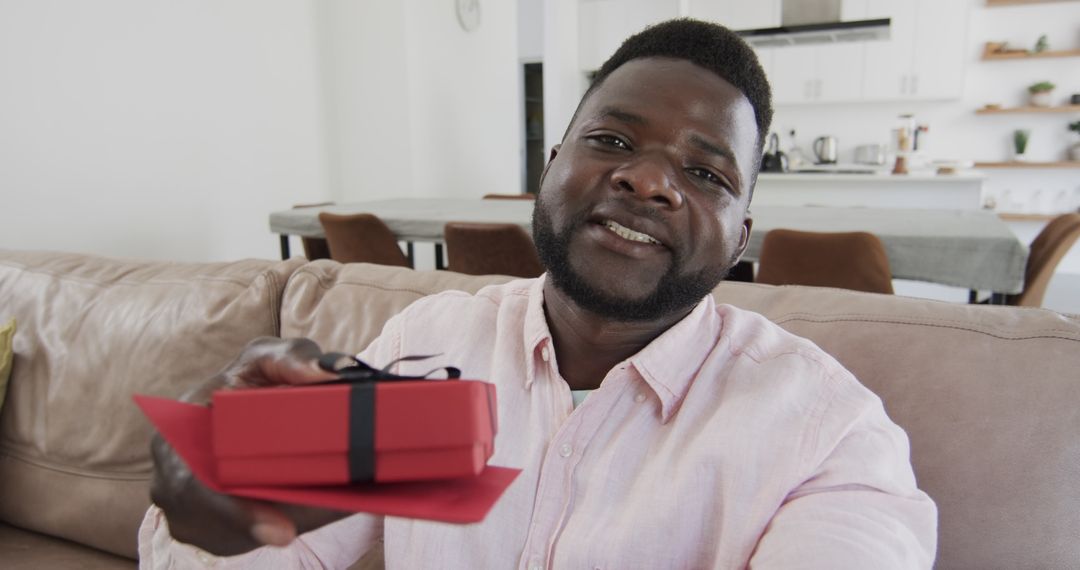 Man Presenting Gift Box in Virtual Call at Home