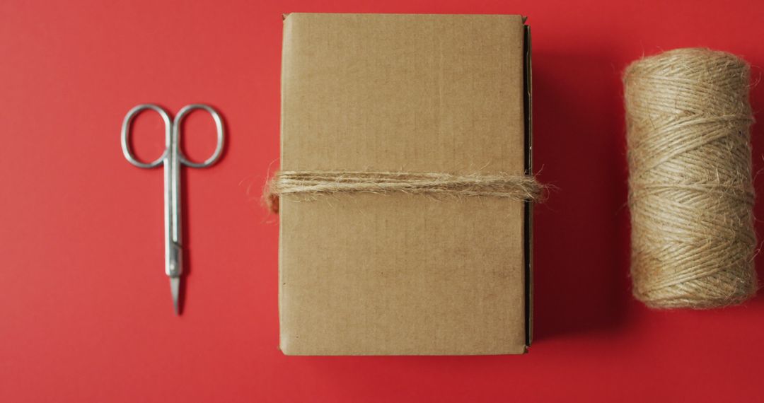 Gift Box Tied with Twine and Metal Scissors on Red Background - Free Images, Stock Photos and Pictures on Pikwizard.com