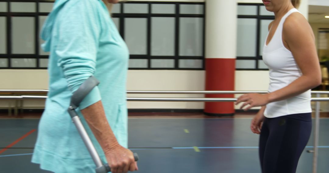 Elderly Woman Walking with Crutches Assisted by Physiotherapist - Free Images, Stock Photos and Pictures on Pikwizard.com