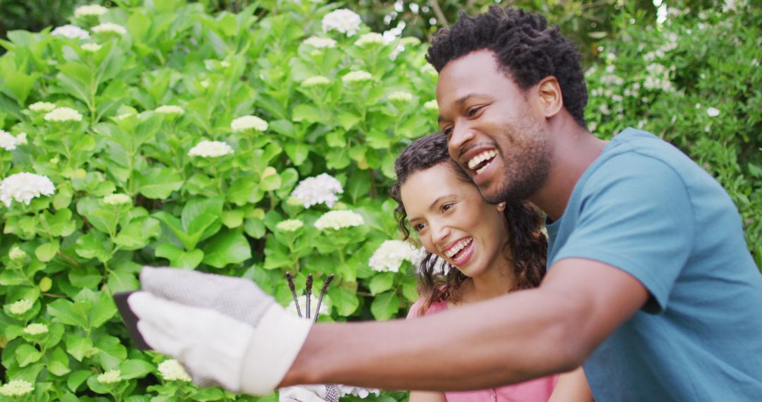 Smiling Biracial Couple Taking Selfie in Garden