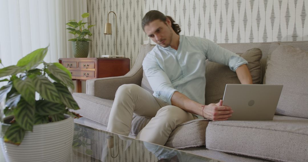 Focused Man Working Remotely on Sofa With Laptop