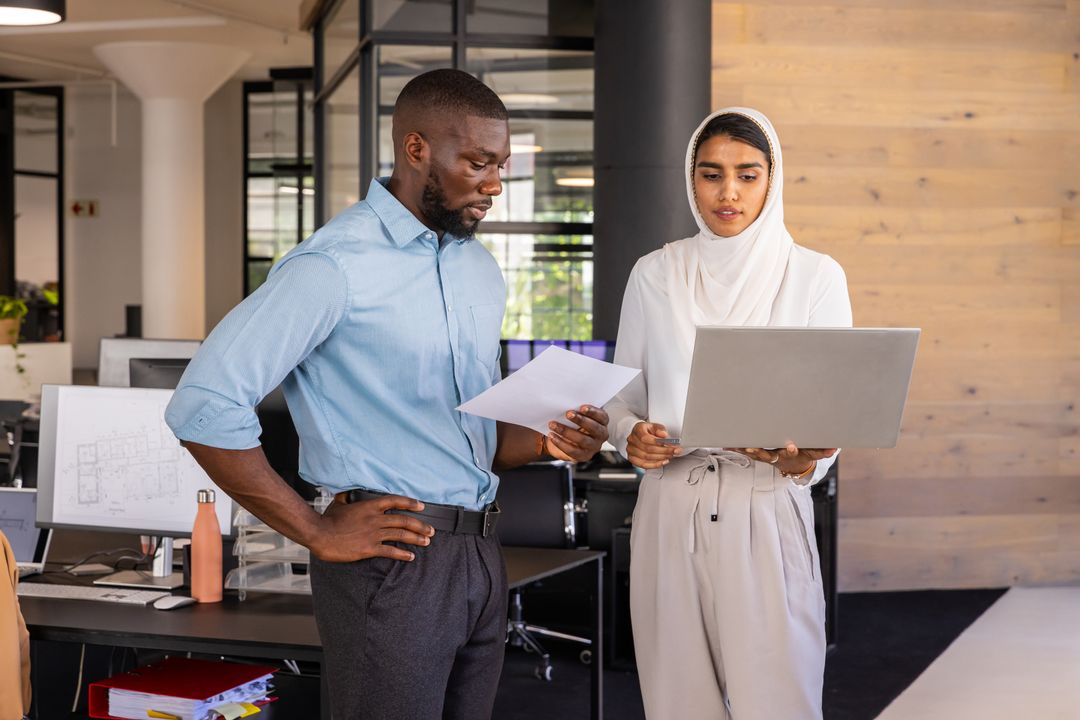 Diverse Professionals Examining Blueprints Together in Modern Office
