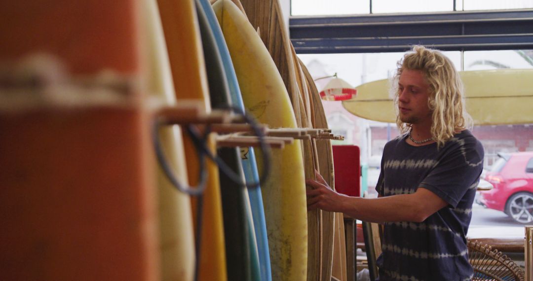 Man browsing surfboards in a surf shop - Free Images, Stock Photos and Pictures on Pikwizard.com