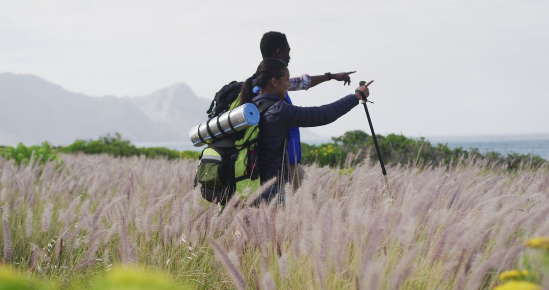 Couple Hiking in Scenic Grassland Pointing at Distant Mountains - Free Images, Stock Photos and Pictures on Pikwizard.com