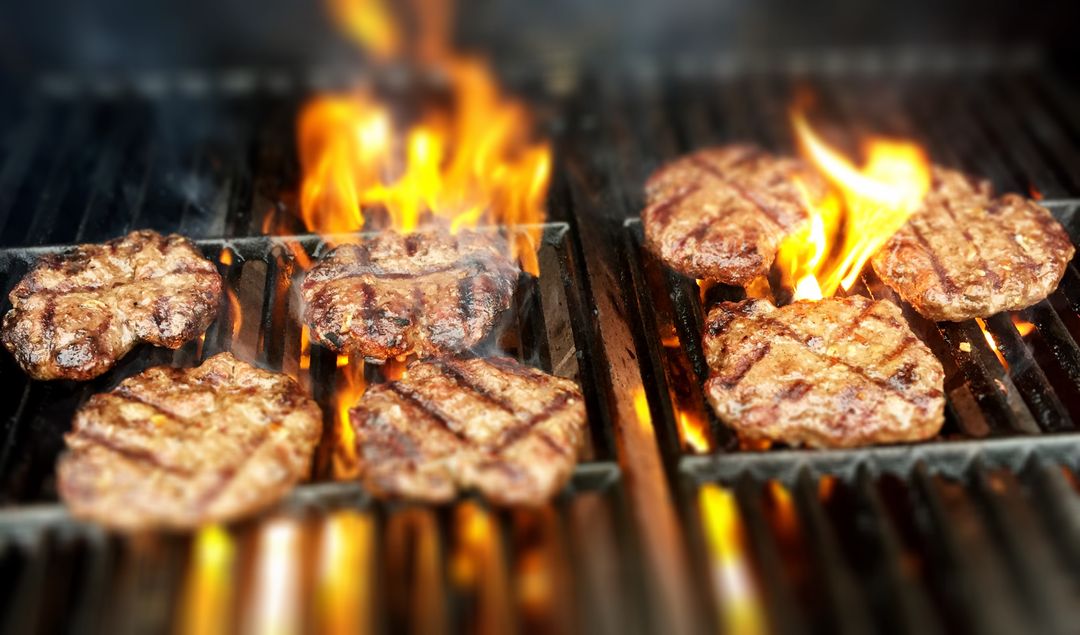 Grilling Juicy Beef Burger Patties Over Flame with Charred Grill Marks and Sizzling Heat