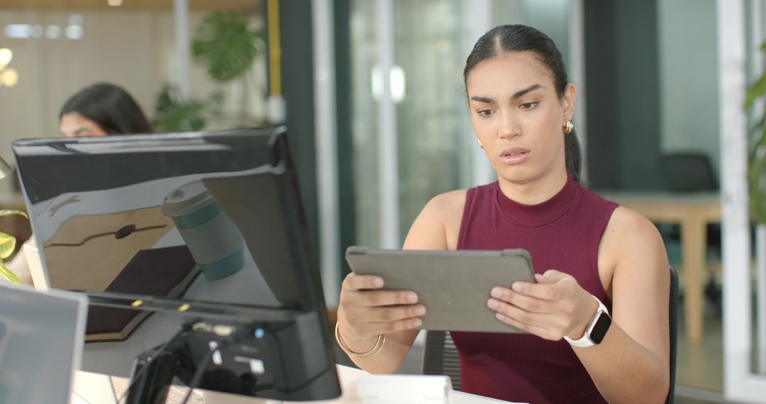 Focused Indian Woman Using Tablet with Smartwatch, Reviewing Work on Desktop in Modern Open-Plan Off