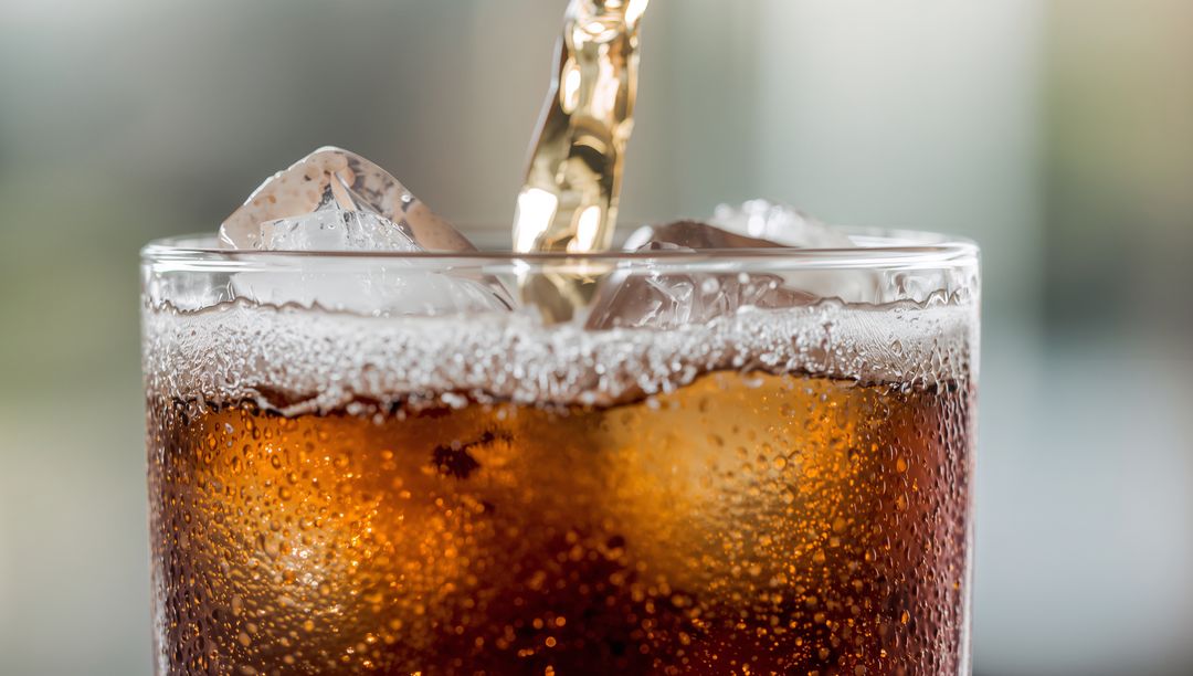 Pouring Cola into Glass with Ice and Condensation