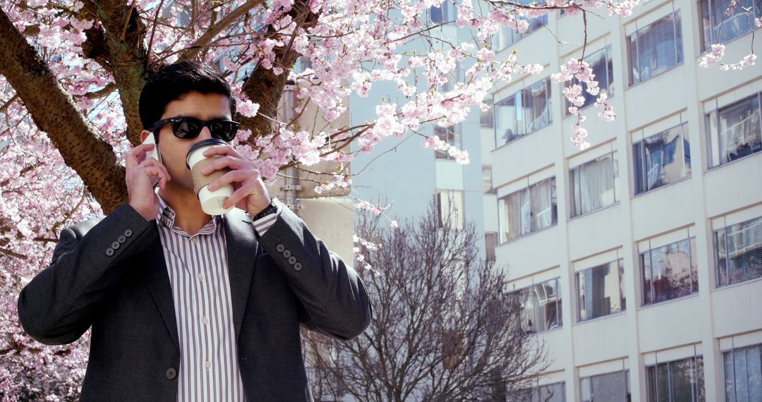 Businessman Enjoying Coffee Under Cherry Blossoms During Spring - Free Images, Stock Photos and Pictures on Pikwizard.com