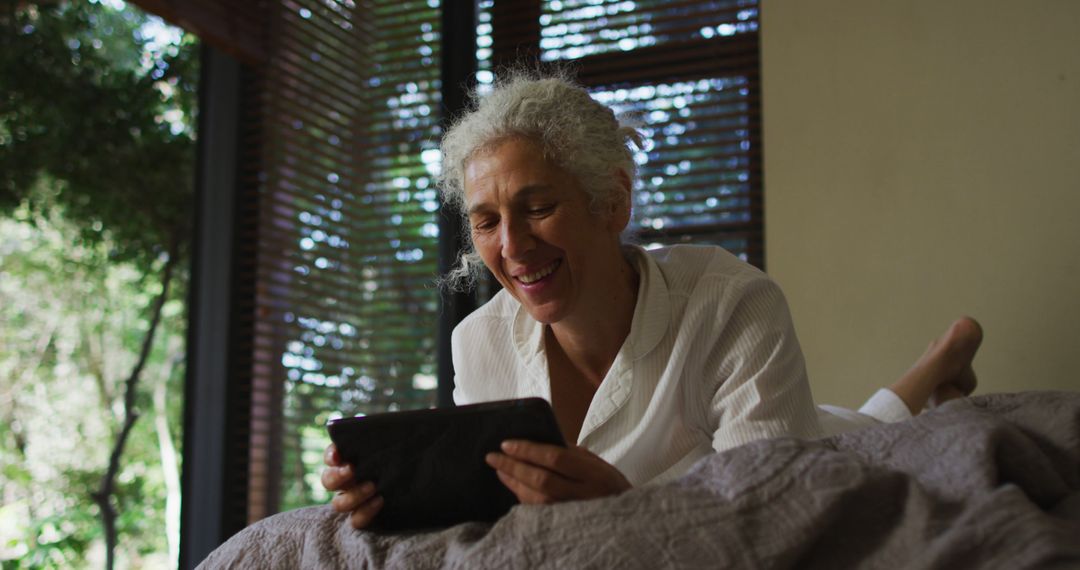 Senior Woman Relaxing and Smiling at Home with Tablet - Free Images, Stock Photos and Pictures on Pikwizard.com