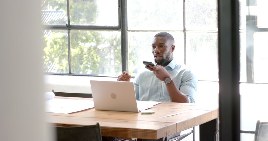 Professional Man Multitasking with Phone and Laptop at Workspace