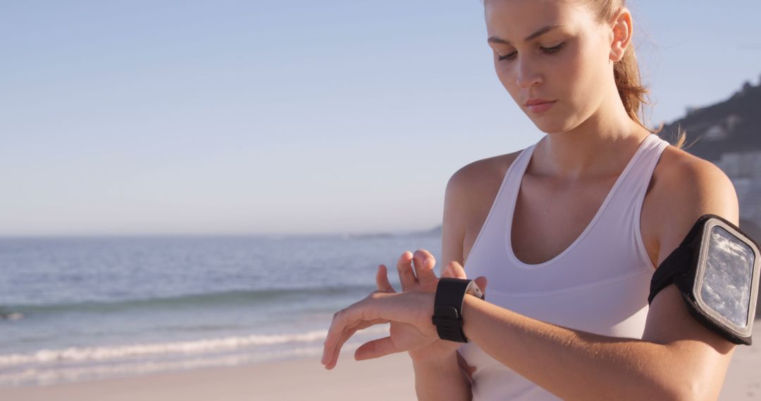 Woman Checking Smartwatch on Beach During Morning Workout - Free Images, Stock Photos and Pictures on Pikwizard.com