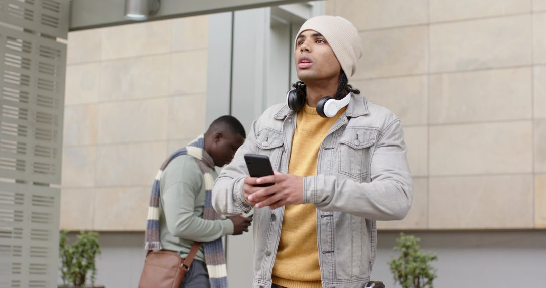Diverse Young Commuter Looking Up While Using Smartphone at Transit Shelter