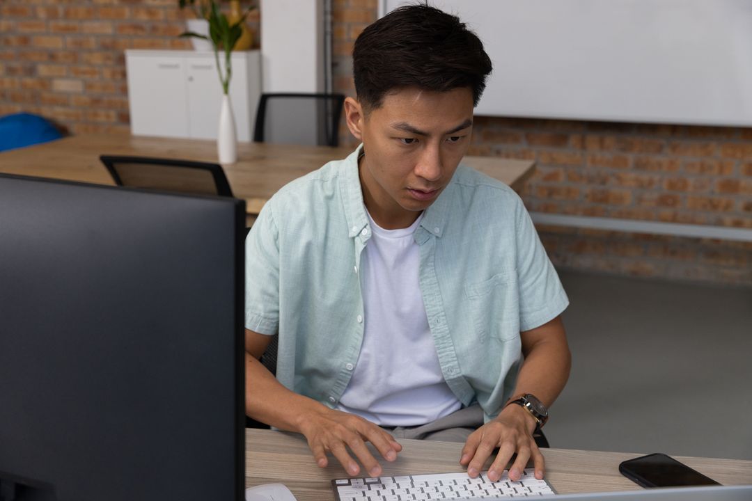 Focused Businessman Typing at Desk in Modern Office Environment