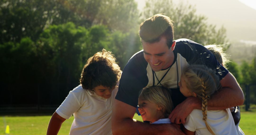 Coach Hugging Happy Children Outdoors on Sunny Day - Free Images, Stock Photos and Pictures on Pikwizard.com