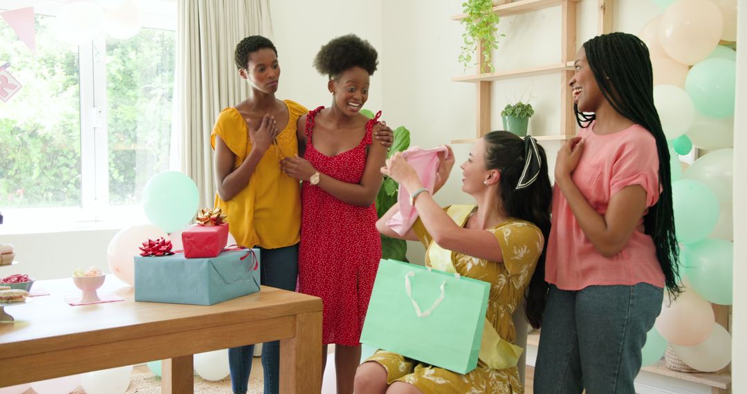 Diverse female friends celebrating birthday with gifts and laughter