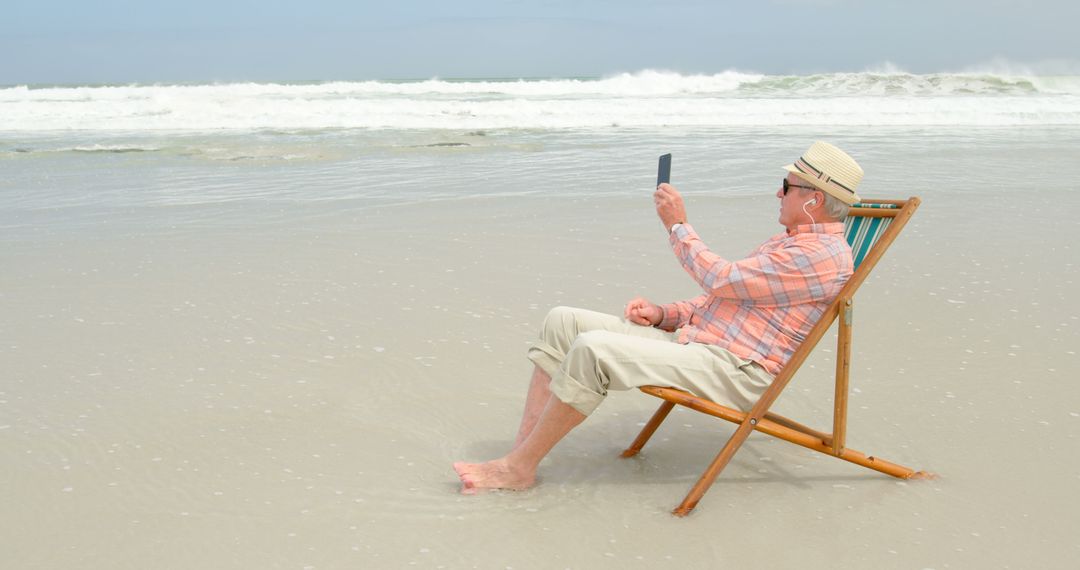 Senior Man Relaxing On Beach Chair While Taking Selfie At Seashore - Free Images, Stock Photos and Pictures on Pikwizard.com