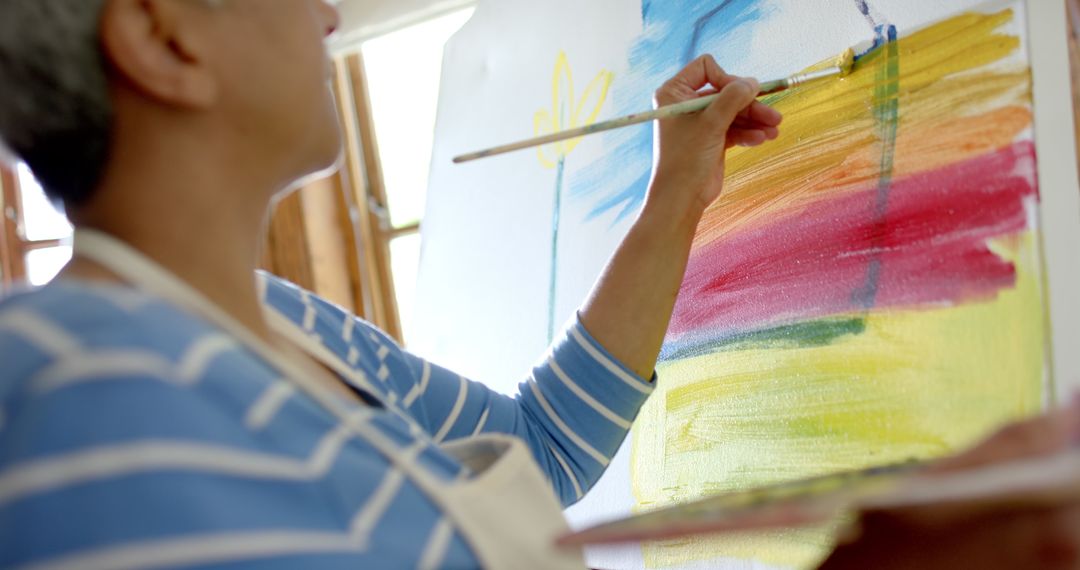 Senior Woman Passionately Painting on Large Canvas in Home Setting