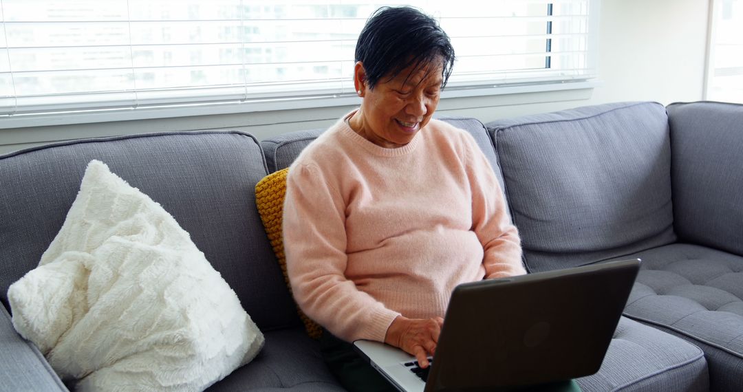 Elderly Woman Using Laptop on Sofa in Bright Living Room - Free Images, Stock Photos and Pictures on Pikwizard.com