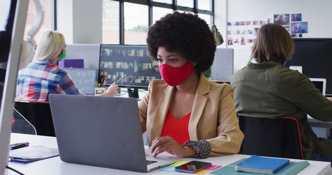 Diverse co-workers wearing masks using laptops in modern office workspace - Free Images, Stock Photos and Pictures on Pikwizard.com