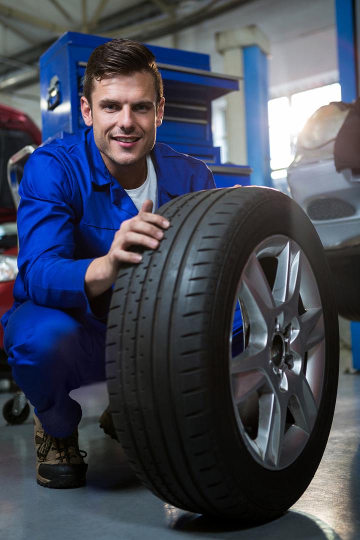 Mechanic examining car tire in automotive repair garage - Free Images, Stock Photos and Pictures on Pikwizard.com