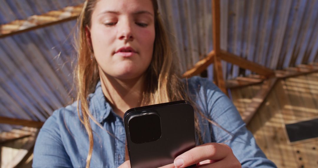 Young Woman Using Smartphone Outdoors, Focused Interaction Under Wooden Structure - Free Images, Stock Photos and Pictures on Pikwizard.com