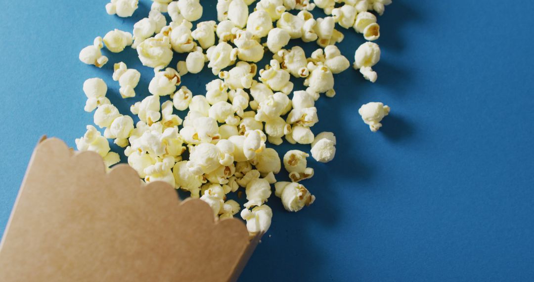 Close-Up Overflowing Popcorn Box on Blue Background with Copy Space - Free Images, Stock Photos and Pictures on Pikwizard.com