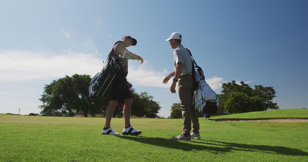 Two Golfers Carrying Golf Bags on Lush Green Golf Course Talking - Free Images, Stock Photos and Pictures on Pikwizard.com