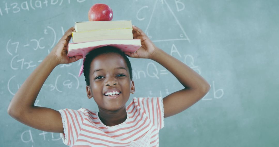 Joyful Child Balancing Books and Apple in Classroom