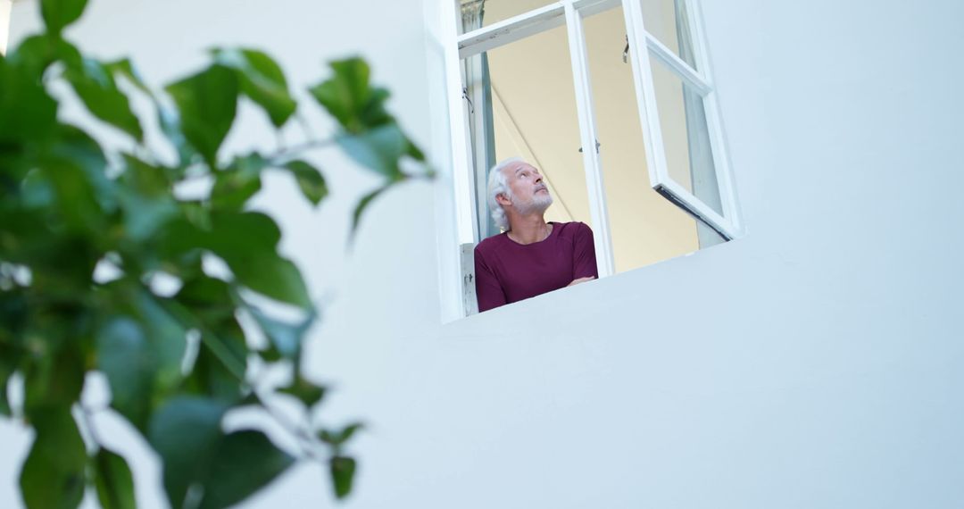 Contemplative Man Gazing Out Window in Bright Home - Free Images, Stock Photos and Pictures on Pikwizard.com