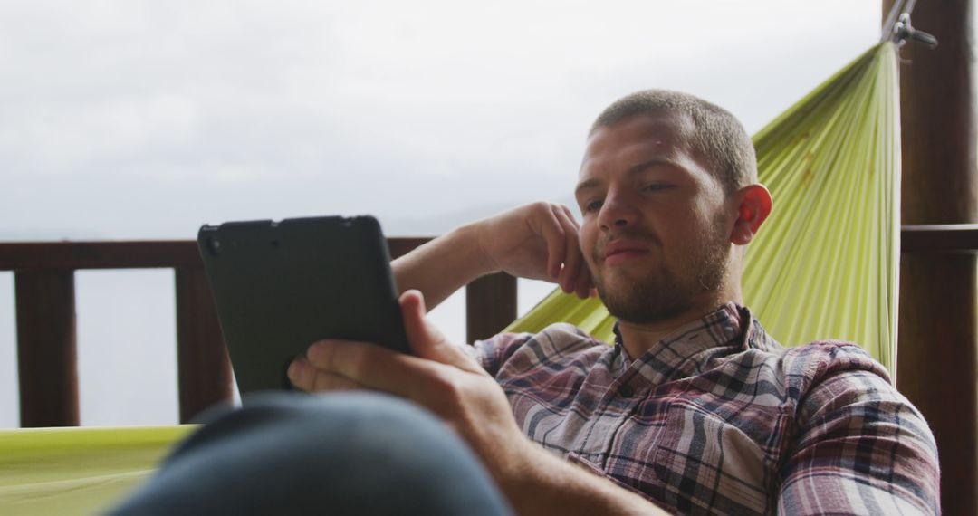 Man Relaxing in Hammock While Using Tablet on Balcony - Free Images, Stock Photos and Pictures on Pikwizard.com