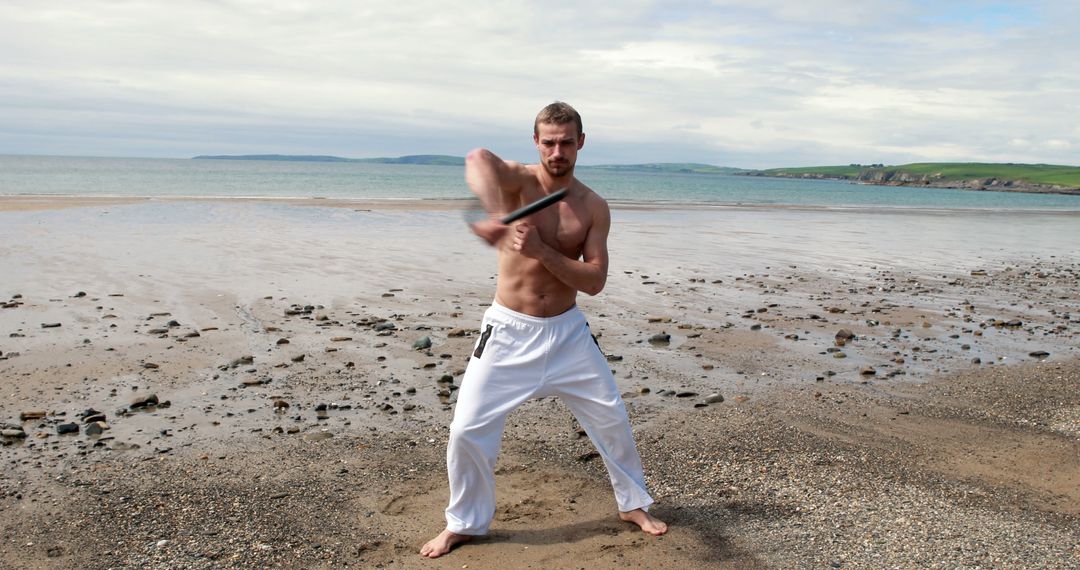 Man Practicing Martial Arts With Bo Staff on Sandy Beach - Free Images, Stock Photos and Pictures on Pikwizard.com