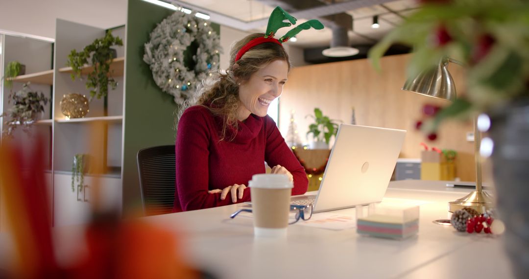 Woman in Office Wearing Reindeer Antlers and Smiling at Laptop During Christmas Season - Free Images, Stock Photos and Pictures on Pikwizard.com