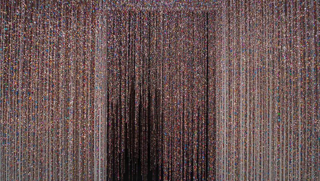 Shimmering multicolor bead curtain creating vertical light lines and dark central passage