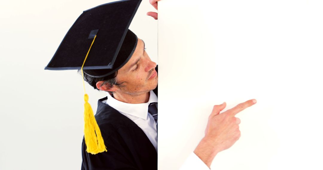 Graduate Pointing at Blank Space Wearing Cap and Gown - Free Images, Stock Photos and Pictures on Pikwizard.com