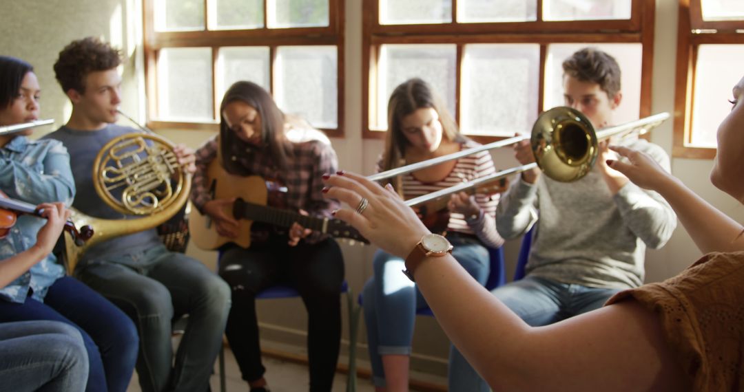 Teenage musicians practicing with female conductor in classroom