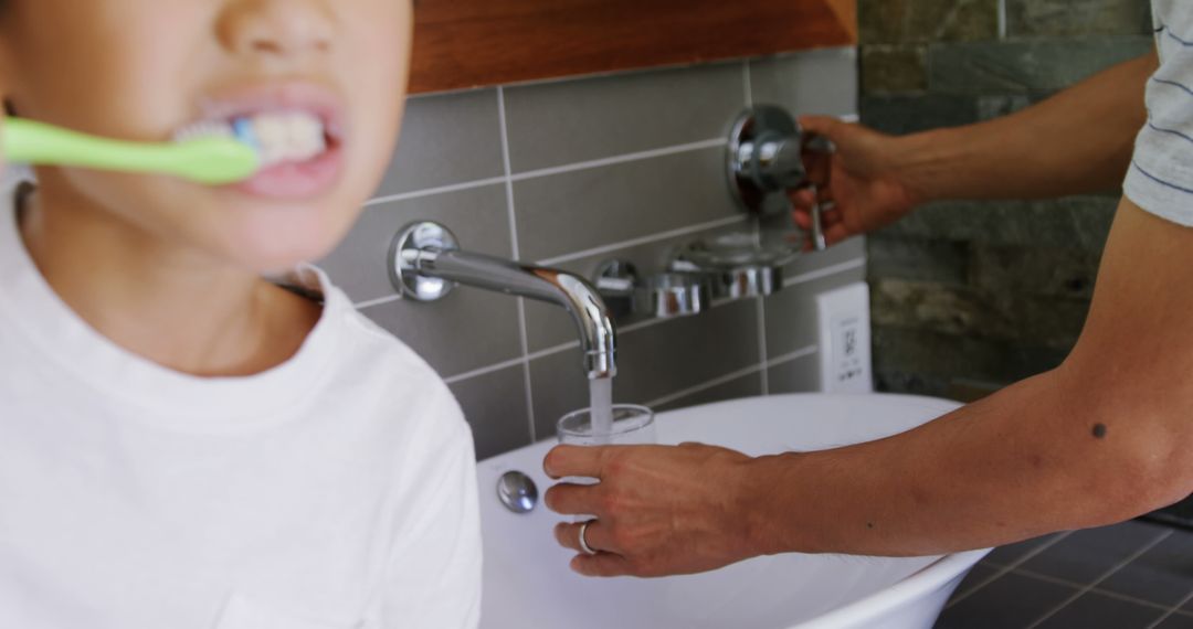 Child Brushing Teeth As Adult Turns Faucet On - Free Images, Stock Photos and Pictures on Pikwizard.com