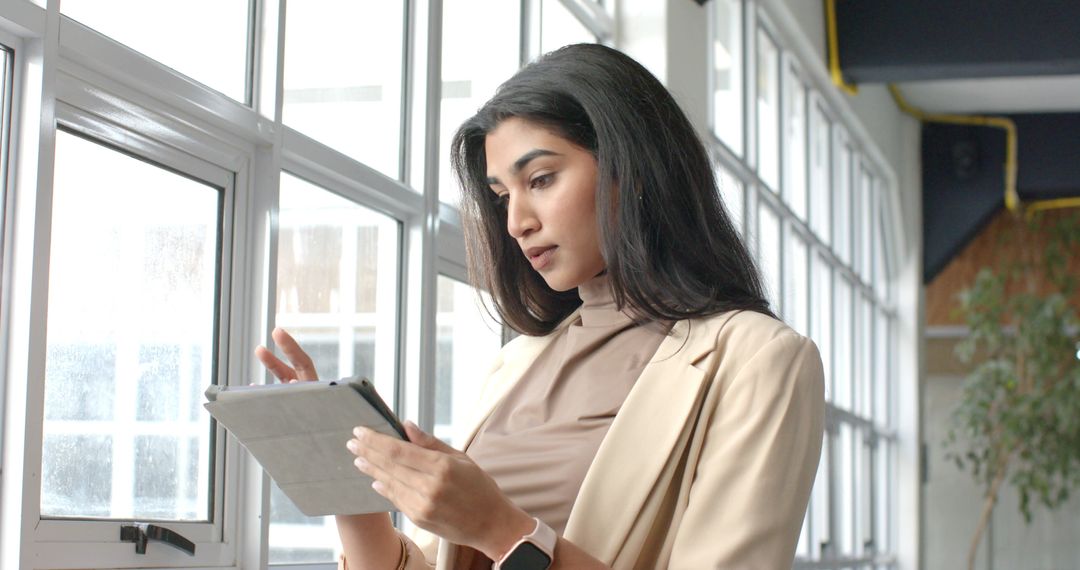 Indian Businesswoman Using Tablet Near Office Windows in Modern Coworking Space