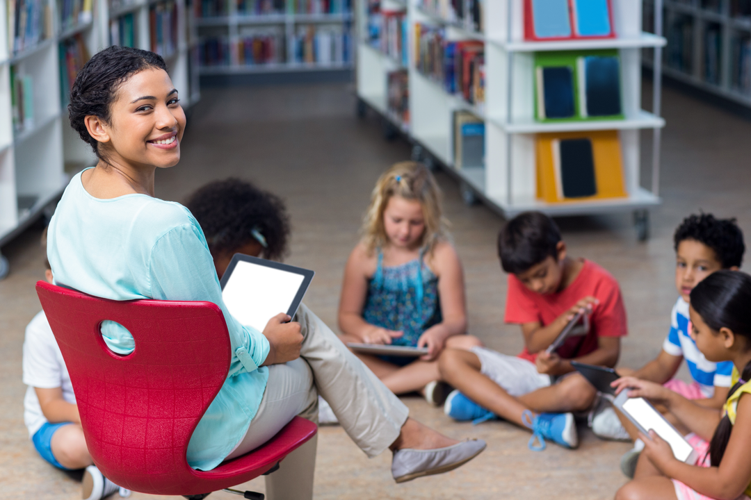 Smiling teacher holding tablet students using digital devices - Download Free Stock Images Pikwizard.com