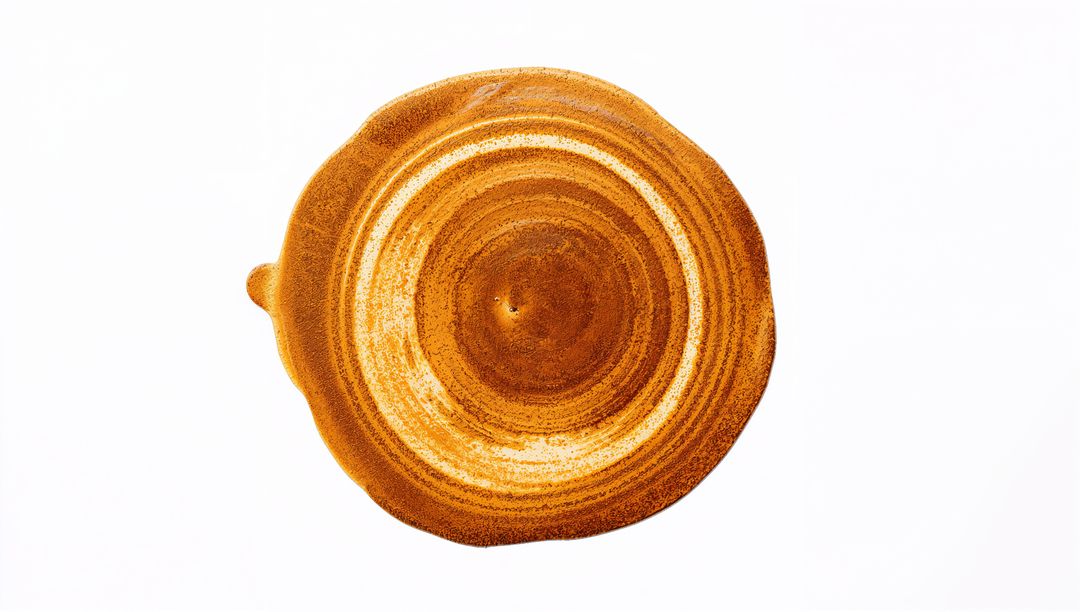 Creating golden-brown concentric paint swirl with subtle left drip on white background