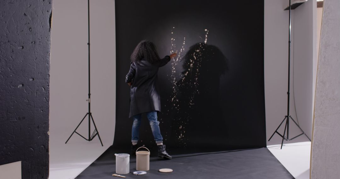 African American Artist Painting Abstract Splatter on Black Backdrop in Creative Studio