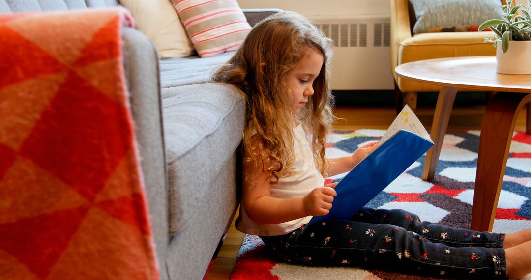 Young Girl Reading Book on Living Room Floor - Free Images, Stock Photos and Pictures on Pikwizard.com