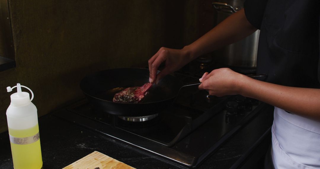 Chef Cooking Steak on Stove in Dimly Lit Kitchen - Free Images, Stock Photos and Pictures on Pikwizard.com