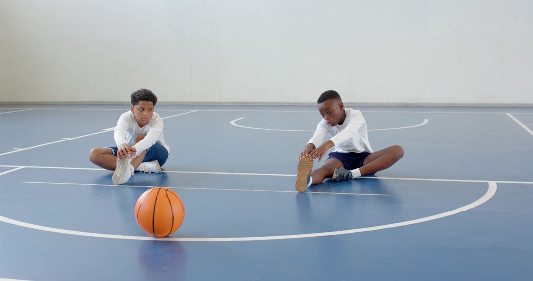Boys Stretching on Basketball Court with Focus on Teamwork
