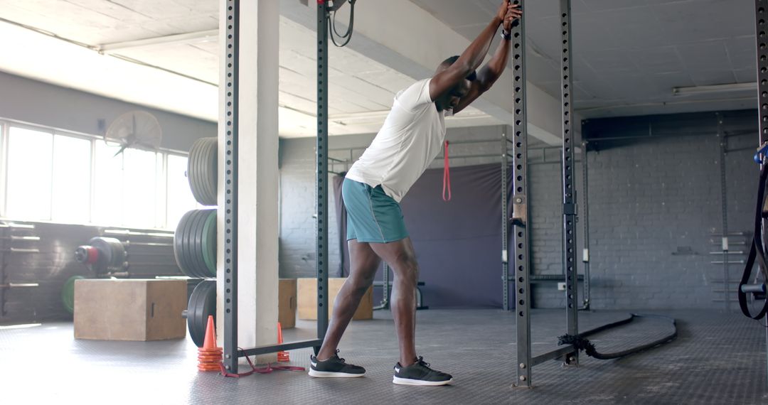 Strong Man Exercising with Resistance Band in Modern Gym