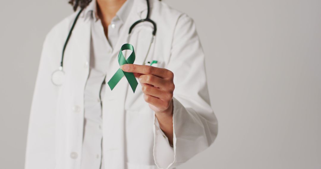 Image of biracial female doctor holding emerald liver cancer ribbon - Free Images, Stock Photos and Pictures on Pikwizard.com