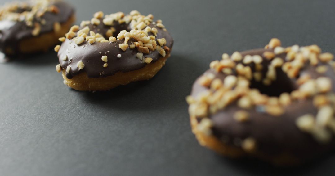 Chocolate Glazed Donuts with Crushed Nut Topping on Dark Background - Free Images, Stock Photos and Pictures on Pikwizard.com