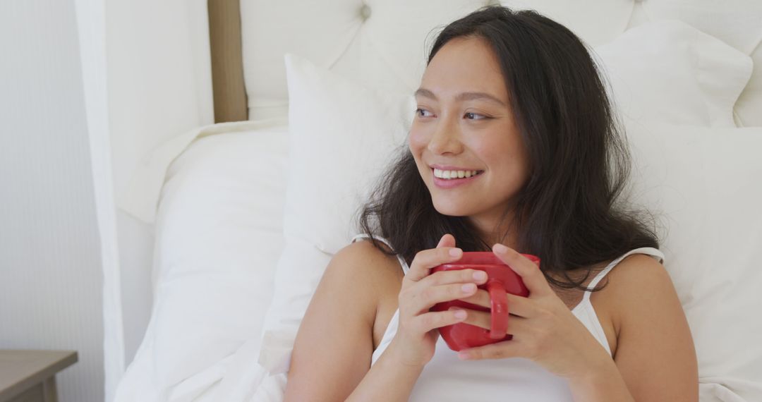 Happy Woman Relaxing in Bed with Red Mug - Free Images, Stock Photos and Pictures on Pikwizard.com